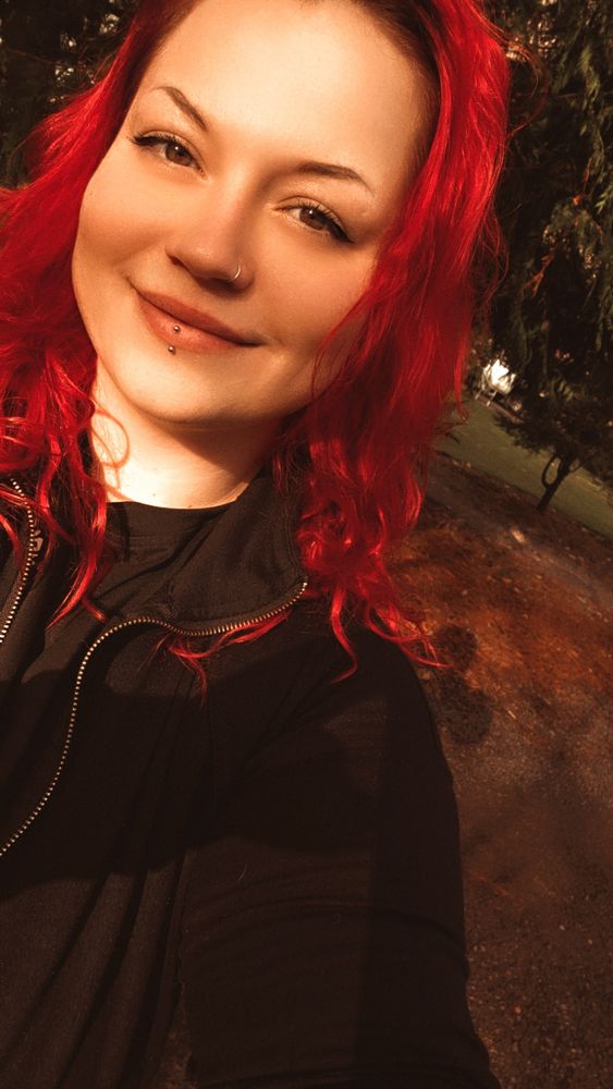 Selfie of Sandy wearing a black zip up with the sun shining on her face on her nature walk before dinner