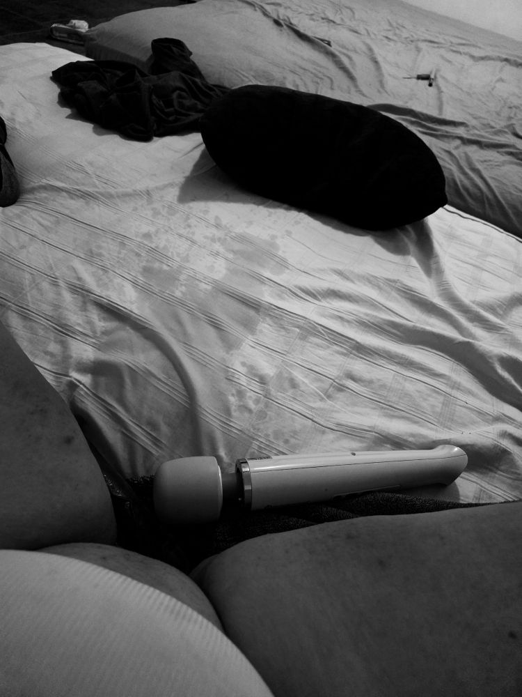 A picture of Sandy's on the bed, legs spread with her Hitachi wand in between her thighs. You can see she squirted all over the bed.