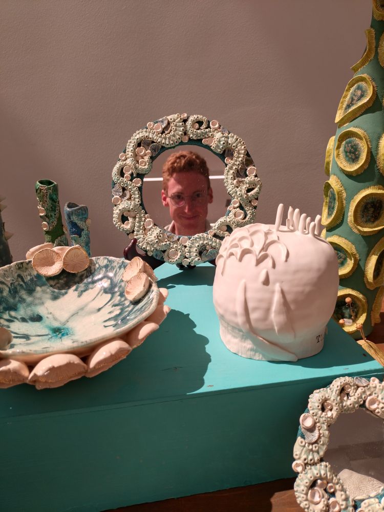 Display of maritime-themed pottery art with me looking in a mirror framed by octopus arms