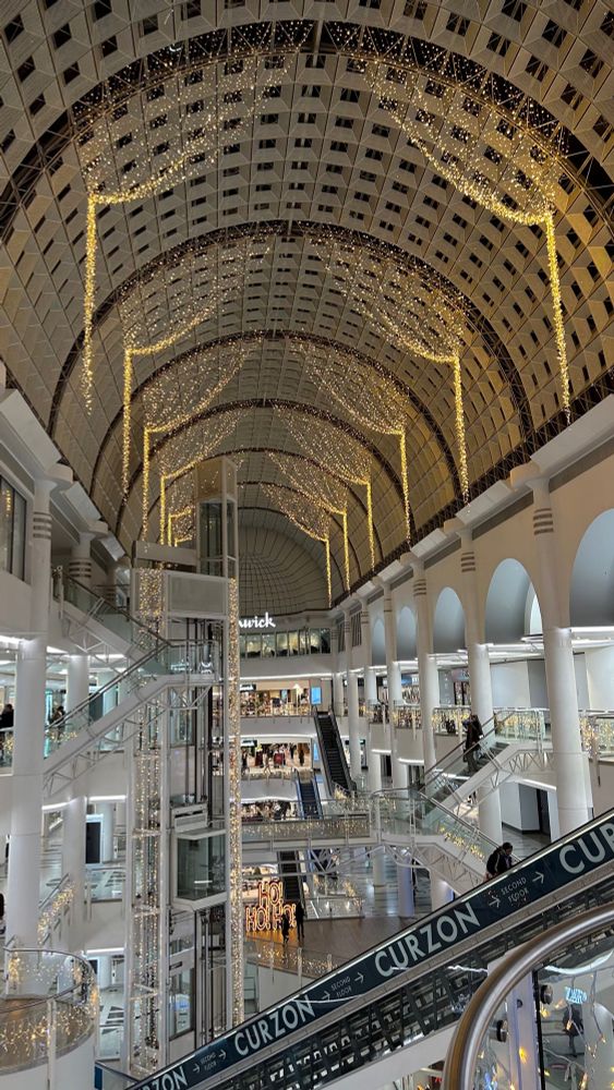A shopping centre decorated for Christmas. Illuminated golden curtains are falling from the ceiling.