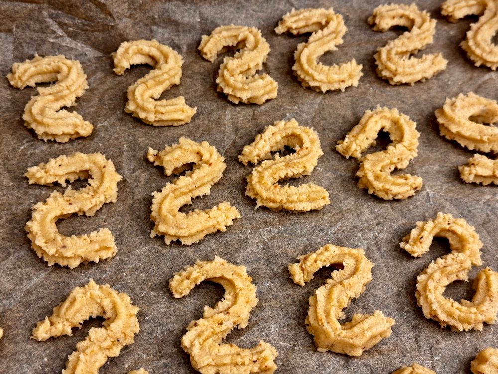 Serpentine shaped spritz biscuits on a tray, about to be baked.