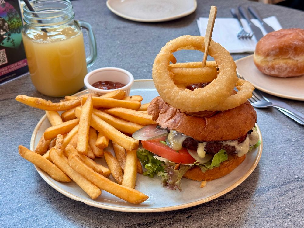 A plate with a burger and fries. A small plate with a jam donut on the side.