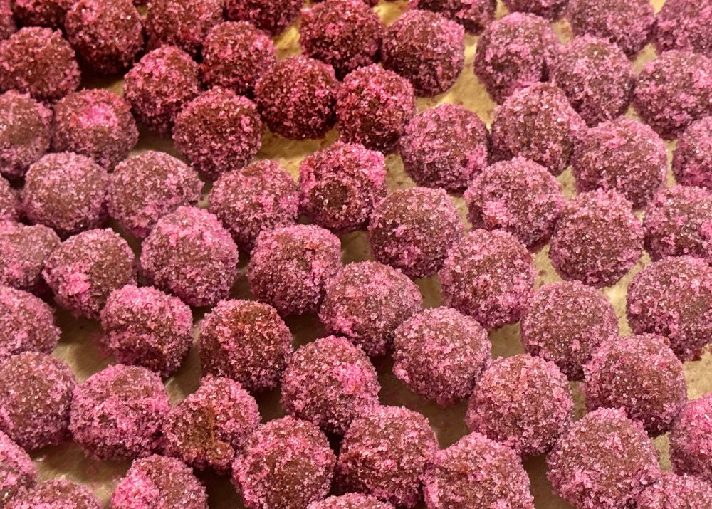 Many chocolate truffles coated with pink  crystals.