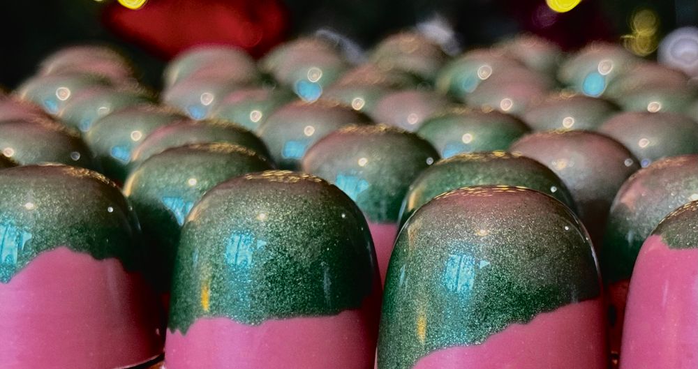 Rows of shiny green and pink chocolates
