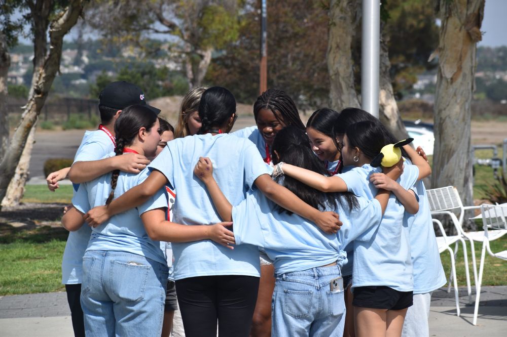 Group of Red Cross youth standing in a circle in a park. 