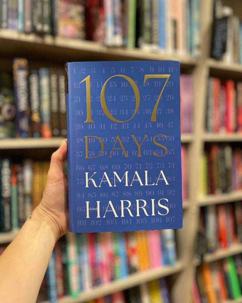 A photo of a hand holding the book, "107 Days" by Kamala Harris in front of a bookshelf.
---
https://www.blue-house-books.com/item/DFe05H_njq6EgAihyCYCqw

For the first time, and with surprising and revealing insights, former Vice President Kamala Harris tells the story of one of the wildest and most consequential presidential campaigns in American history.

Your Secret Service code name is Pioneer.
You are the first woman in history to be elected vice president of the United States.
On July 21, 2024, your running mate, Joe Biden, announces that he will not be seeking reelection.
The presidential election will occur on November 5, 2024.
You have 107 days.

From the chaos of campaign strategy sessions to the intensity of debate prep under relentless scrutiny and the private moments that rarely make headlines, Kamala Harris offers an unfiltered look at the pressures, triumphs, and heartbreaks of a history-defining race. With behind-the-scenes details and a voice that is both intimate and urgent, this is more than a political memoir—it’s a chronicle of resilience, leadership, and the high stakes of democracy in action.

Written with candor, a unique perspective, and the pace of a page-turning novel, 107 Days takes you inside the race for the presidency as no one has ever done before.