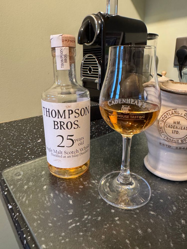 A bottle and glass of a 25 year old Laphroaig single malt whisky bottled by Thompson Brothers