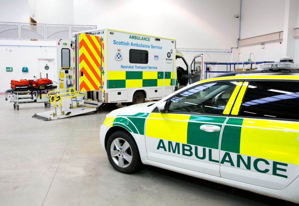 Two ambulance vehicles parked inside - one is a neonatal transport ambulance van and the other is an ambulance response car.