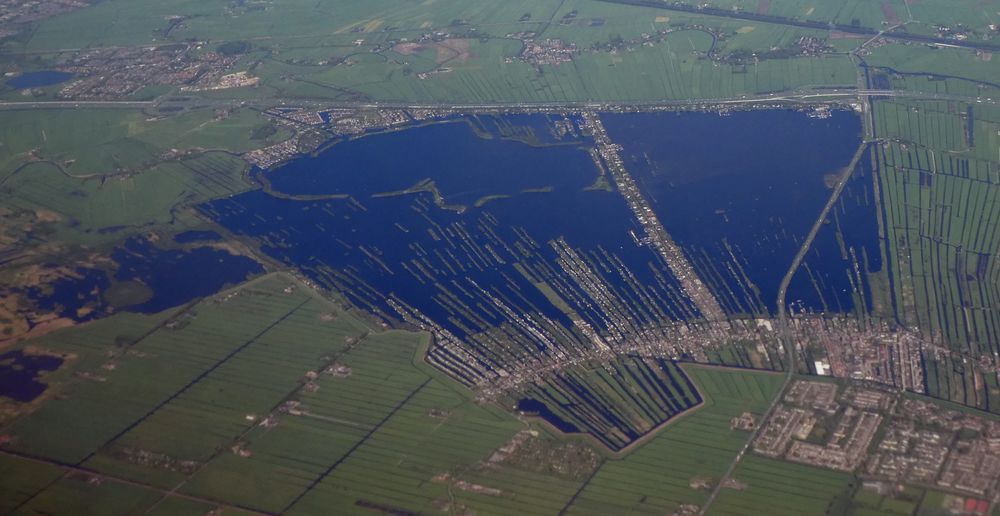 aerial photo of the same pie-slice-shaped lake crossed by dozens of thin, straight strips of land with buildings