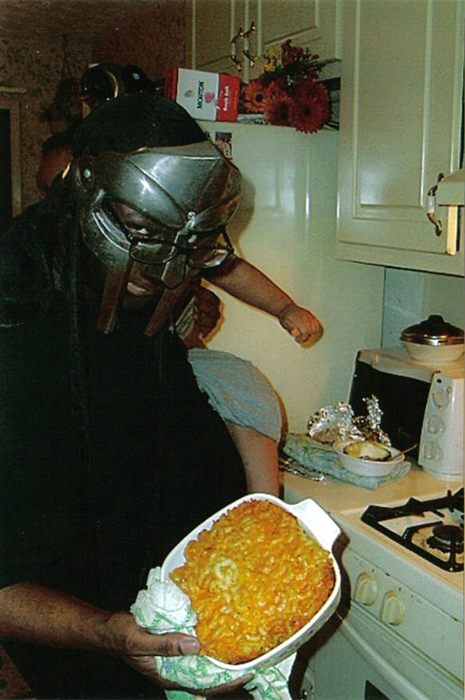 MF DOOM holding his villainous mac & cheese while holding his son with his other arm