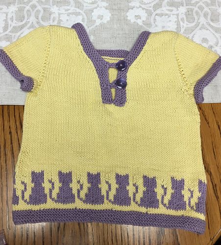 A yellow toddler sweater, with purple cats sitting along the hem.  Pattern is "Cat Person", yarn is Debbie Bliss Eco Baby cotton