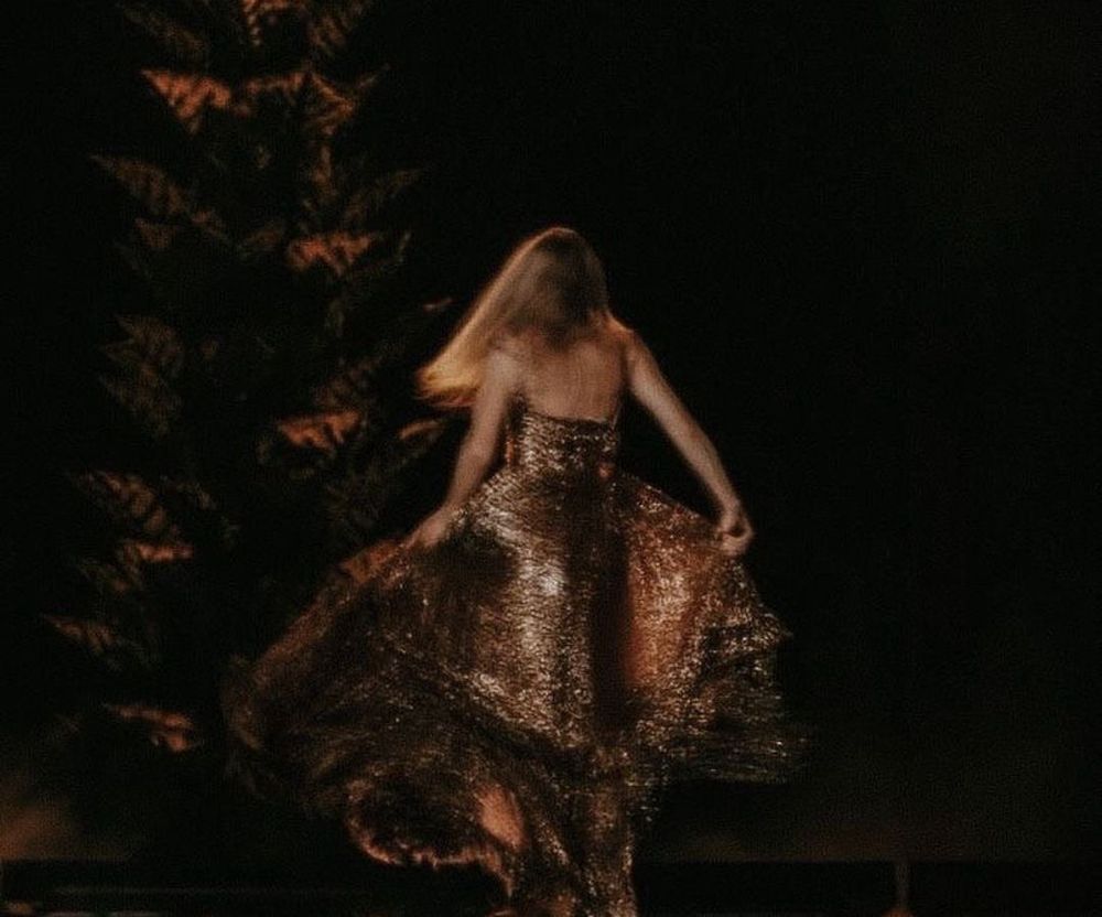 Taylor Swift wearing the bronze evermore dress on the Eras Tour from behind 
