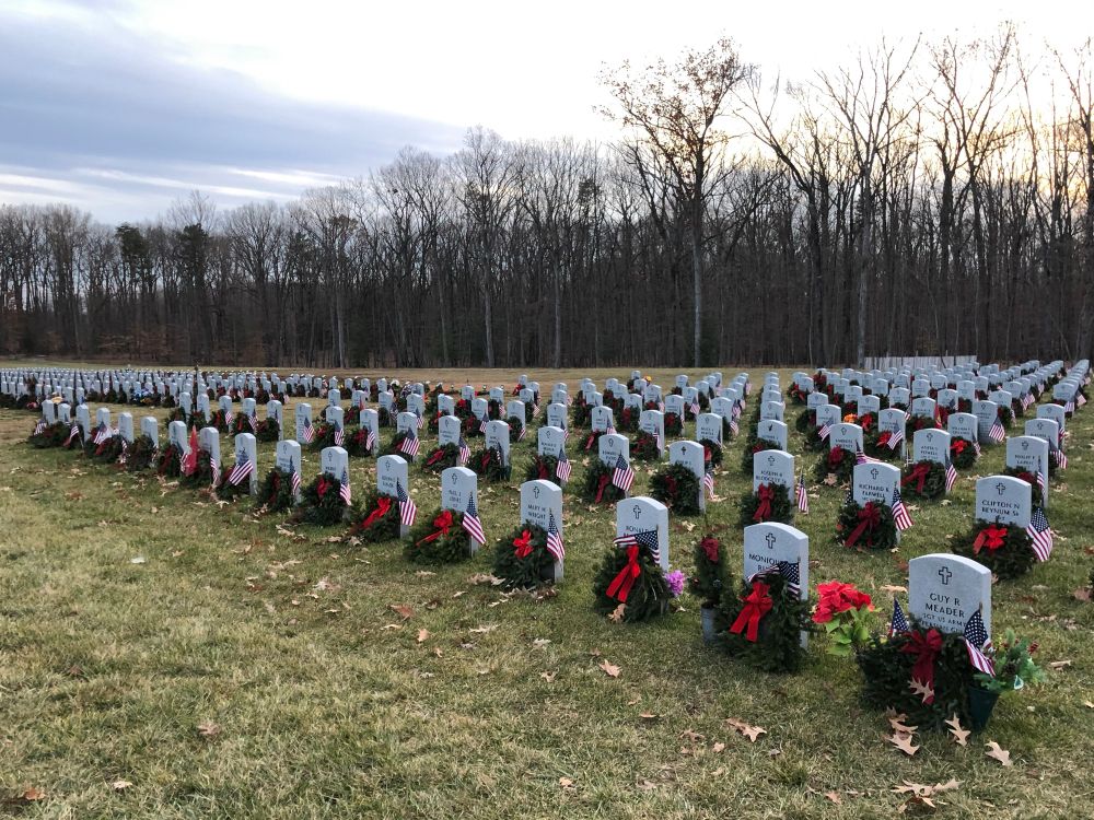 Quantico National Military Cemetery at Xmas with green wreaths in from of individual headstones. Over 100 headstones all the same size & shape in many rows.   