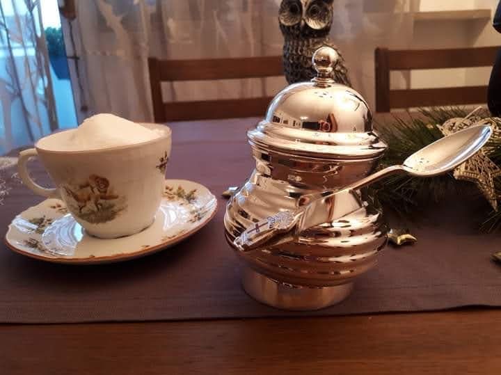 Picture of a sugar pot with roughly humanoid posture, holding a spoon