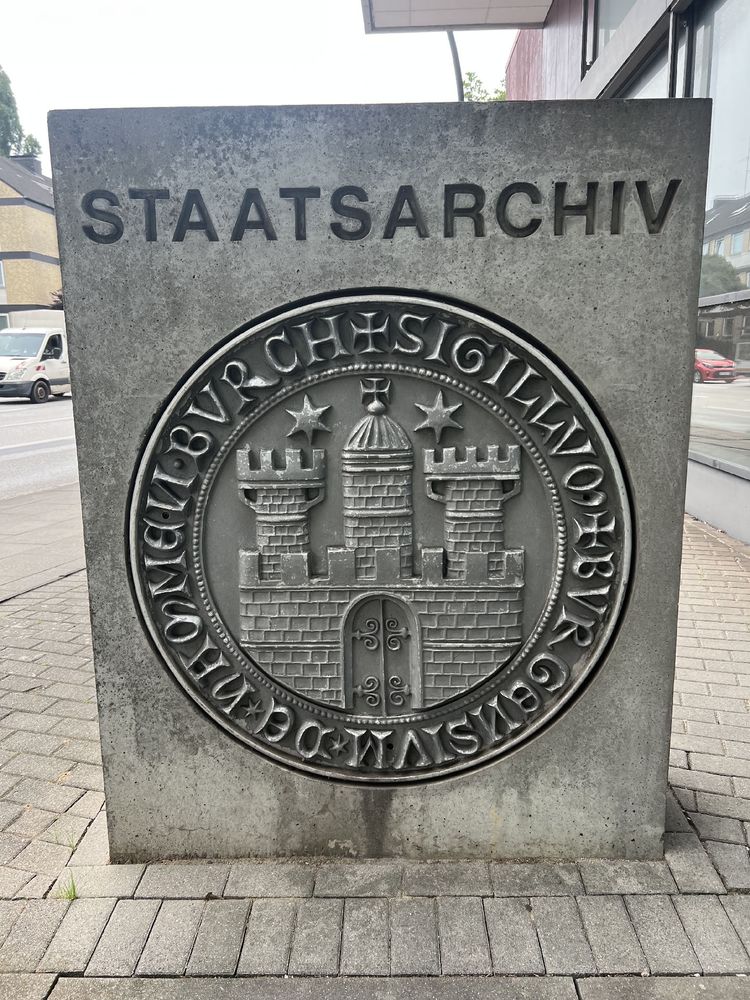 Foto einer riesigen Steinplatte mit reliefartig hineingemeißeltem Wappen des Hamburger Staatsarchivs.
