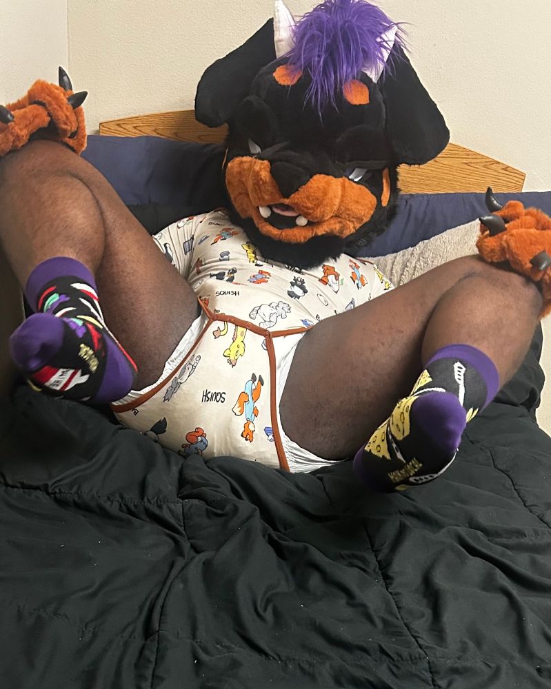 Biscuit spreading his legs out while looking at the viewer, inviting the viewer for a sniff of his soggy diaper.