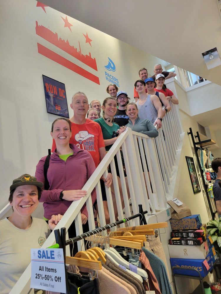 fourteen members of DC Road Runners standing on a staircase in the Pacers Running store in Georgetown. Joseph P. Fisher (center left) just offered a training seminar. He is concerned that his hairline is obviously receding in most pictures.