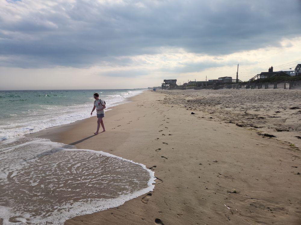 A person walks on Charlestown Town Beach in Rhode Island on a summer late afternoon.