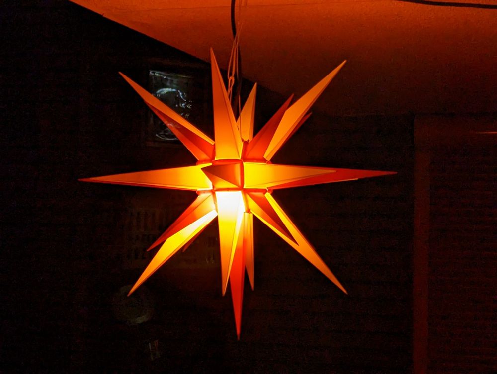 Herrnhuter Stern in Rot-Tönen mit Gelb im Dunkel