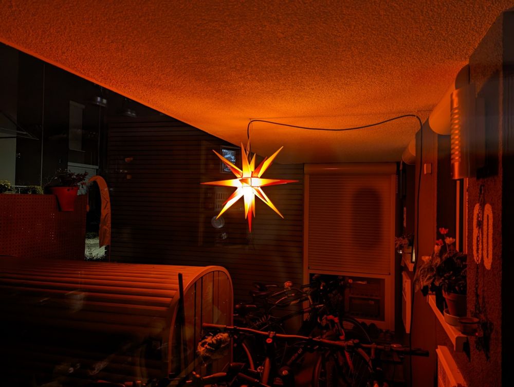 Herrnhuter Stern in Rot-Tönen hängt in einem überbauten Eingangsbereich