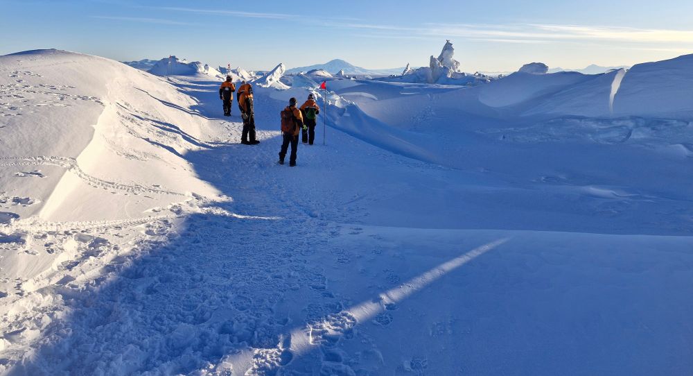 A science team enjoy an evening stroll along the safe, flagged route among the pressure ridges that form each year immediately in front of 🇳🇿 Scott Base. 