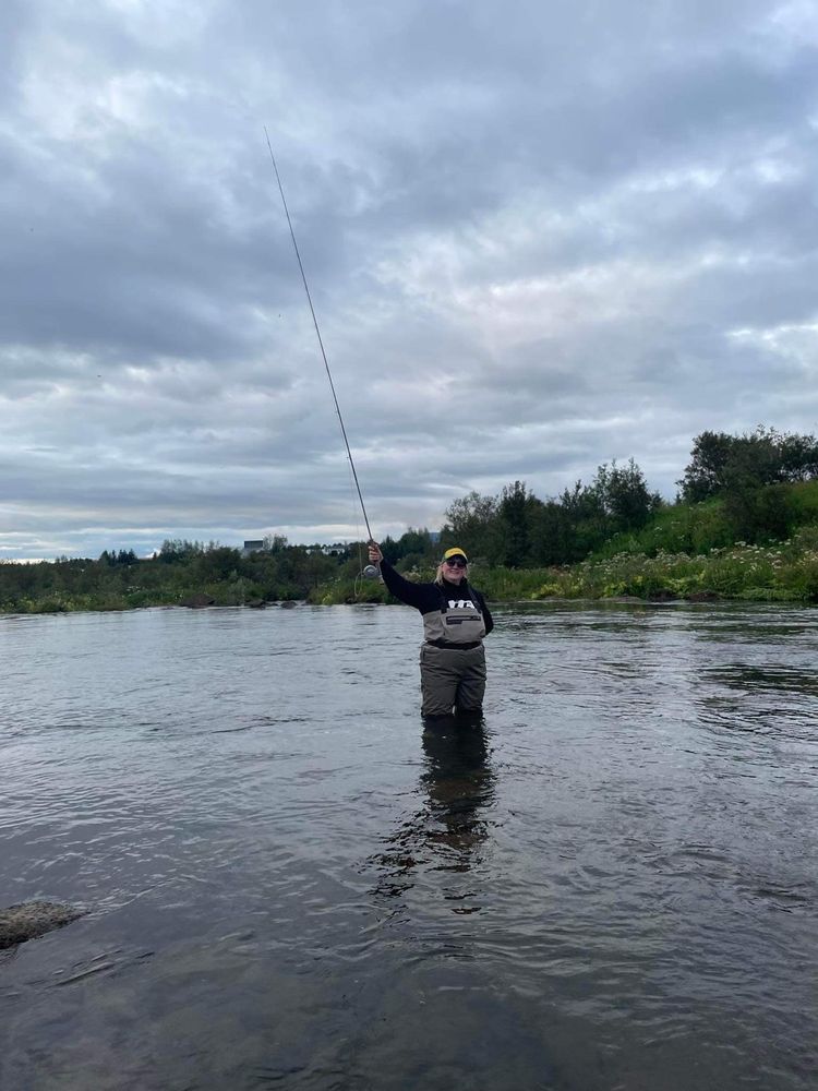 Hófí með veiðistöng standandi í ánni.