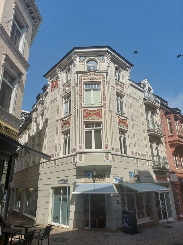 Hellgraues Eckhaus mit bunten Verzierungen im Jugendstil. 