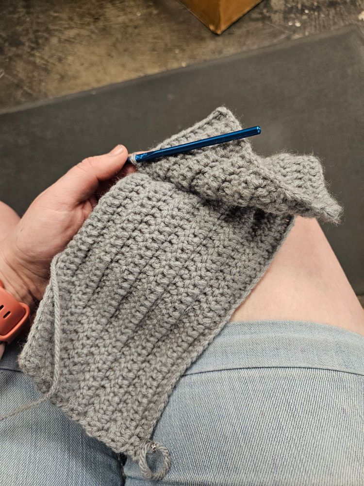 A grey crochet hat in process of being made.