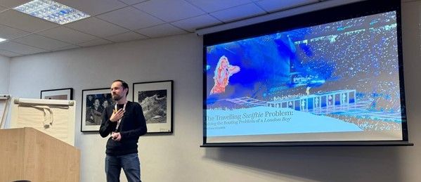 Me, presenting the title slide of my Travelling Swiftie Problem talk, featuring a photo of Taylor Swift performing live on tour.