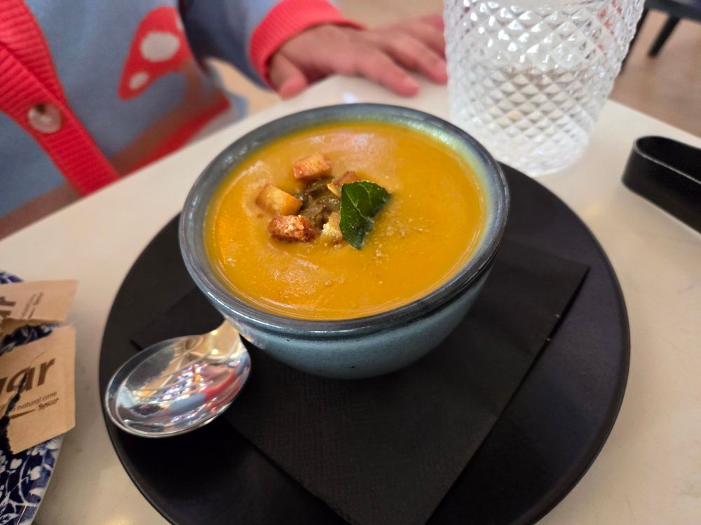 Bowl of butternut squash soup on a black plate. 