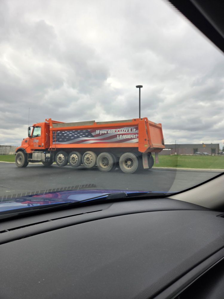Orange truck with an American flag and the message "if you don't love it, leave it."
