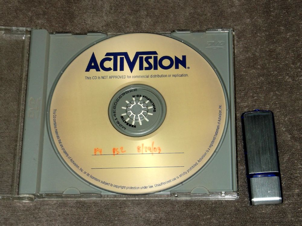 Bad photo of the item I'm selling, an early build of a Fantastic Four game for the PlayStation 2. Disc is a gold colored CD-R in a disc case. The text written on the disc says "F4 PS2 8/29/03" A USB drive is also shown.