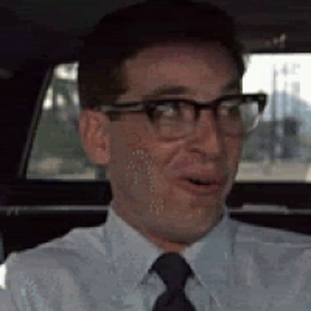 a man wearing glasses and a tie is sitting in a car and making a funny face