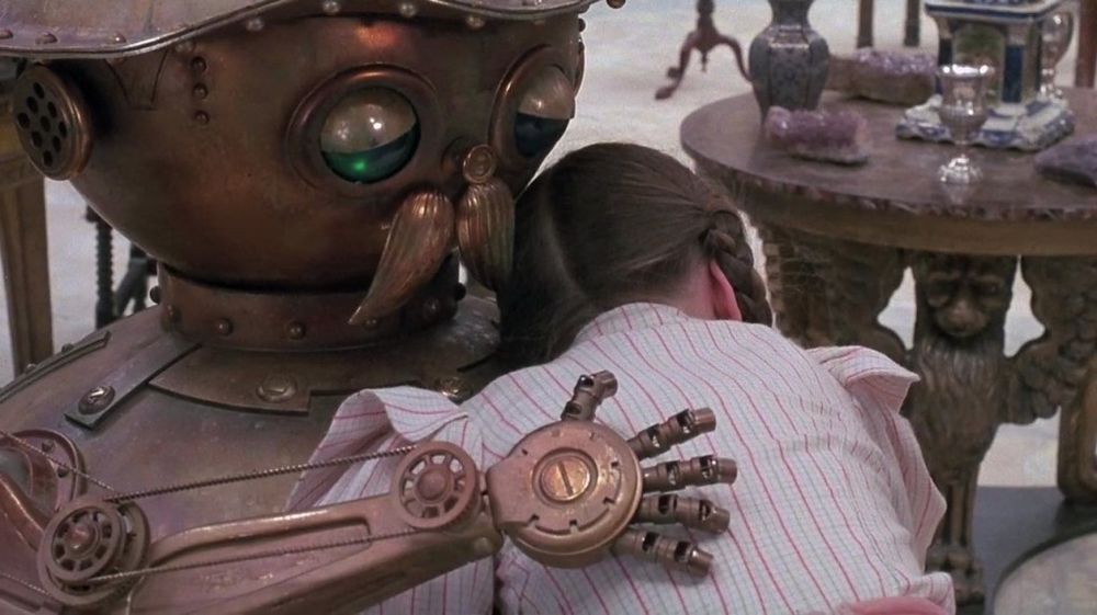 Screenshot from the film Return to Oz. Dorothy hugs Tik Tok, a man made of metal. 