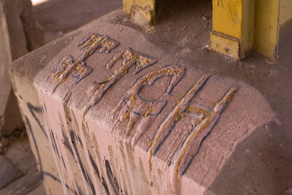 The word "ITCH" affixed to a concrete column in some kind of construction foam or concrete.