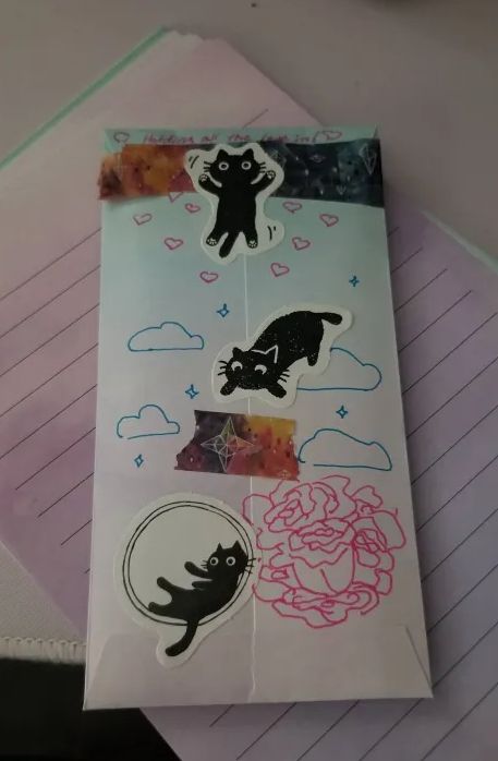 a pastel letter envelope covered in cute cat stickers, washi tape, and doodles