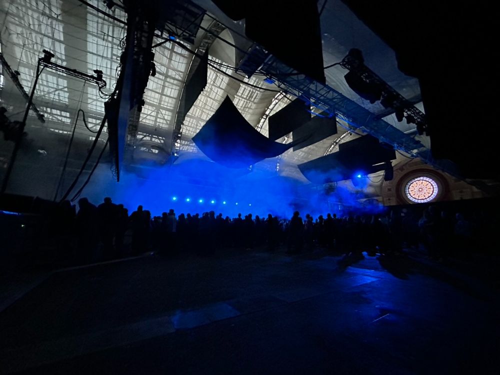 Crowd with blue background and stained glass window at Alexandra Palace.