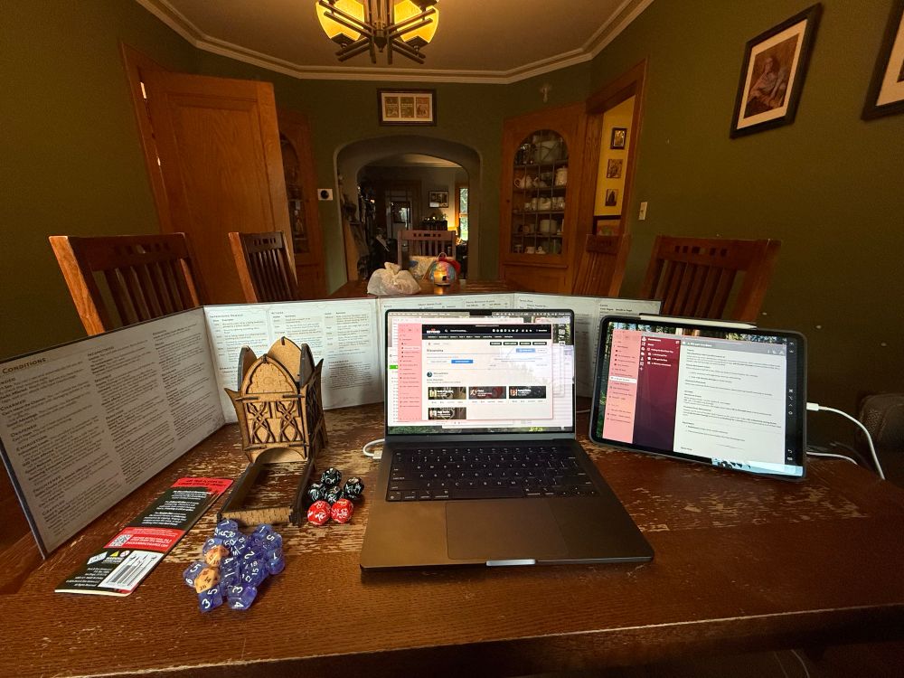 Setup for running my D&D campaign with a computer, iPad, screen, dice and dice tower