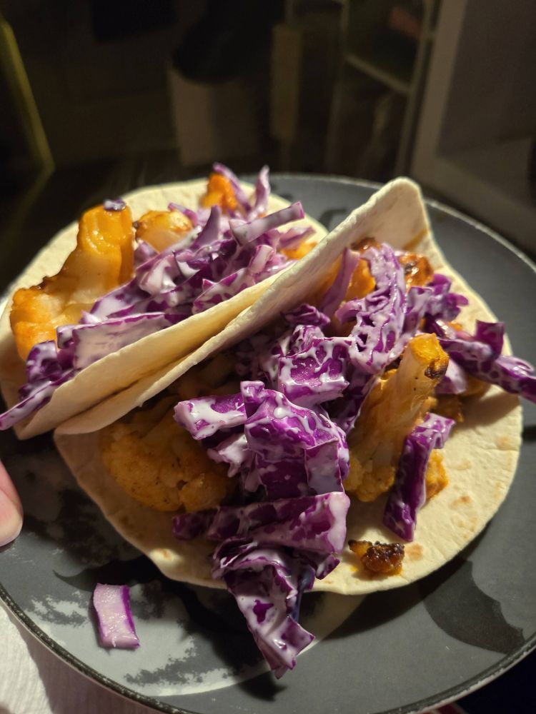 Two flour tortillas with some buffalo cauliflower (no breading) topped with red cabbage coated in ranch.