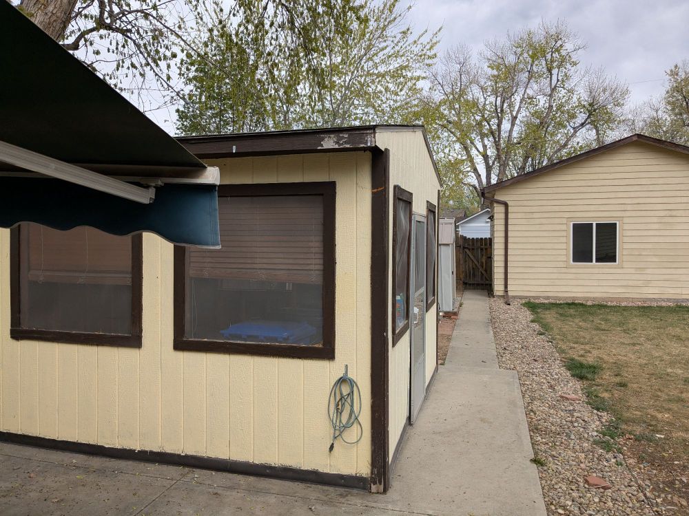 Photo of a back yard, featuring a sun room and a detached garage. 