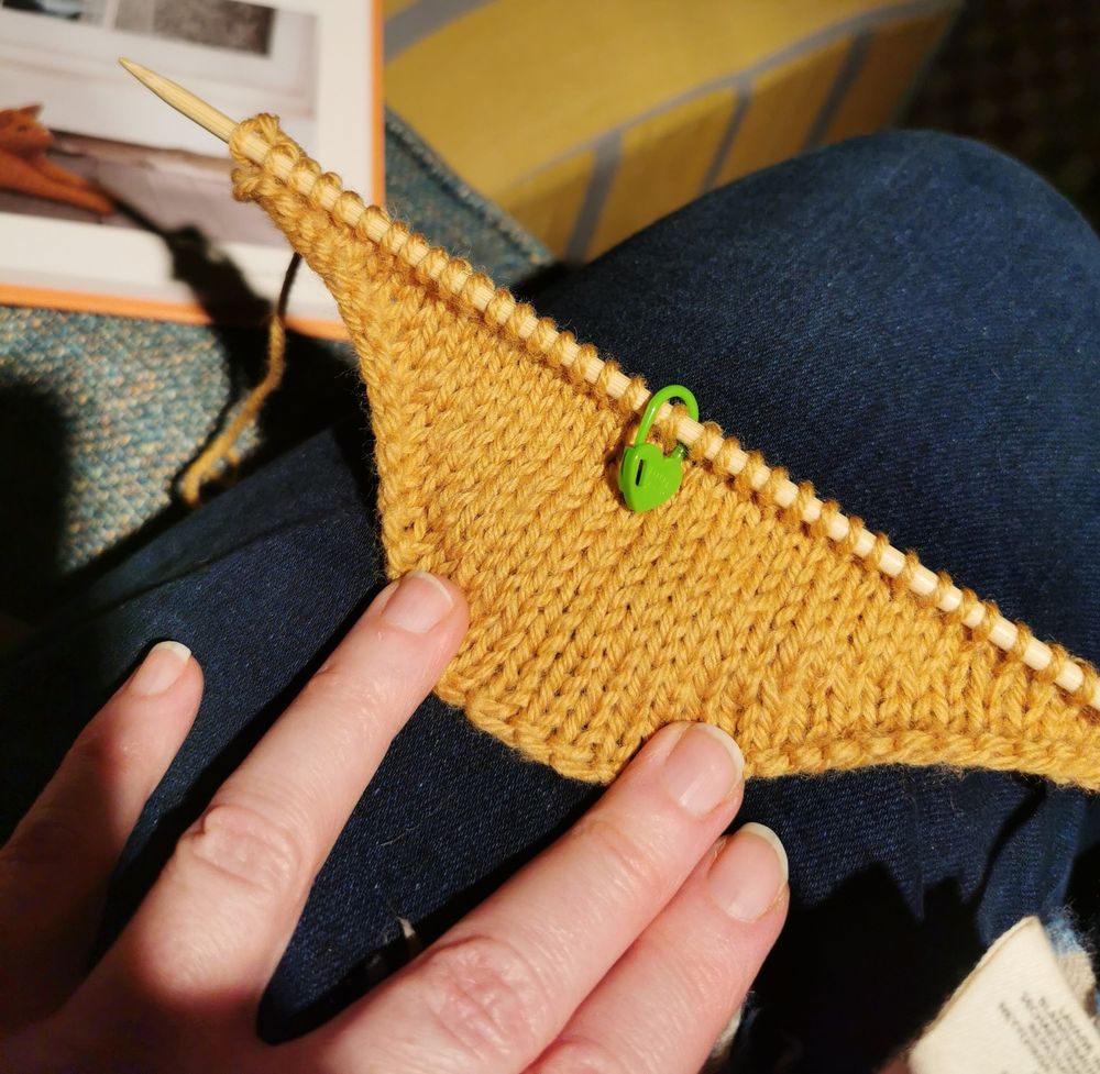 A knitted swatch of ginger wool, with short row shaping giving it a deeply curved hem. 