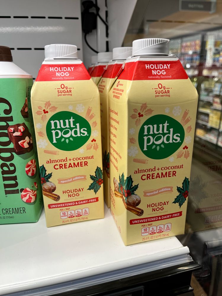 A grocery refrigerator shelf with nut pods brand “Holiday Nog” and Chobani peppermint mocha creamer.