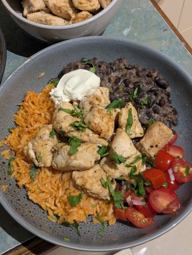 sour cream, pico de gallo, arroz rojo, cuban-style black beans, and pan-fried chicken breast but plated up nice and garnished with coriander