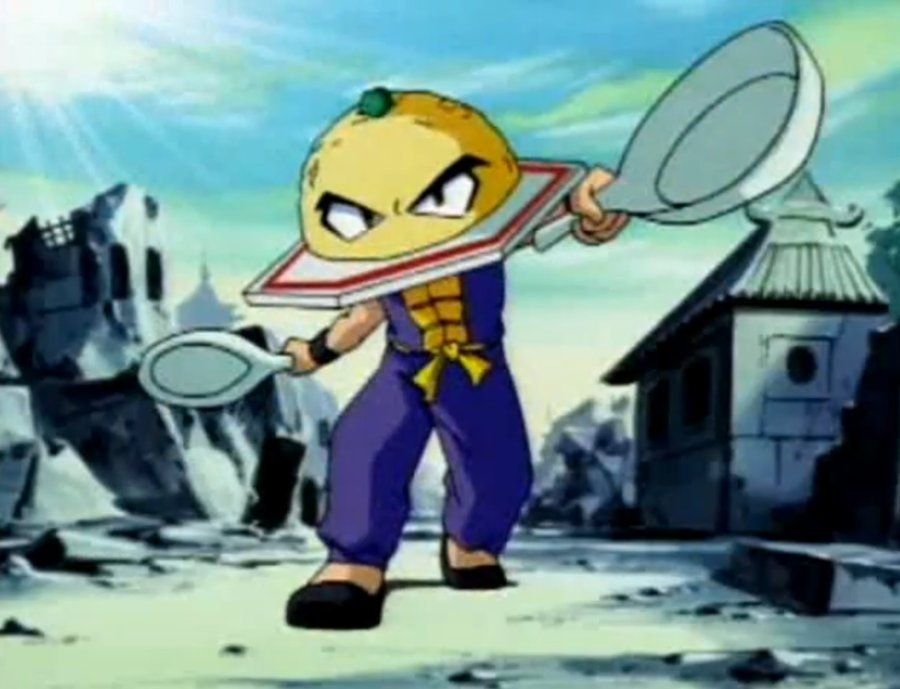 The Fighting Foodons character Fried Ricer, who has a ball of fried rice on a plate for a head stop a human body wearing a blue gi. He has oversized spoons on each hand.
