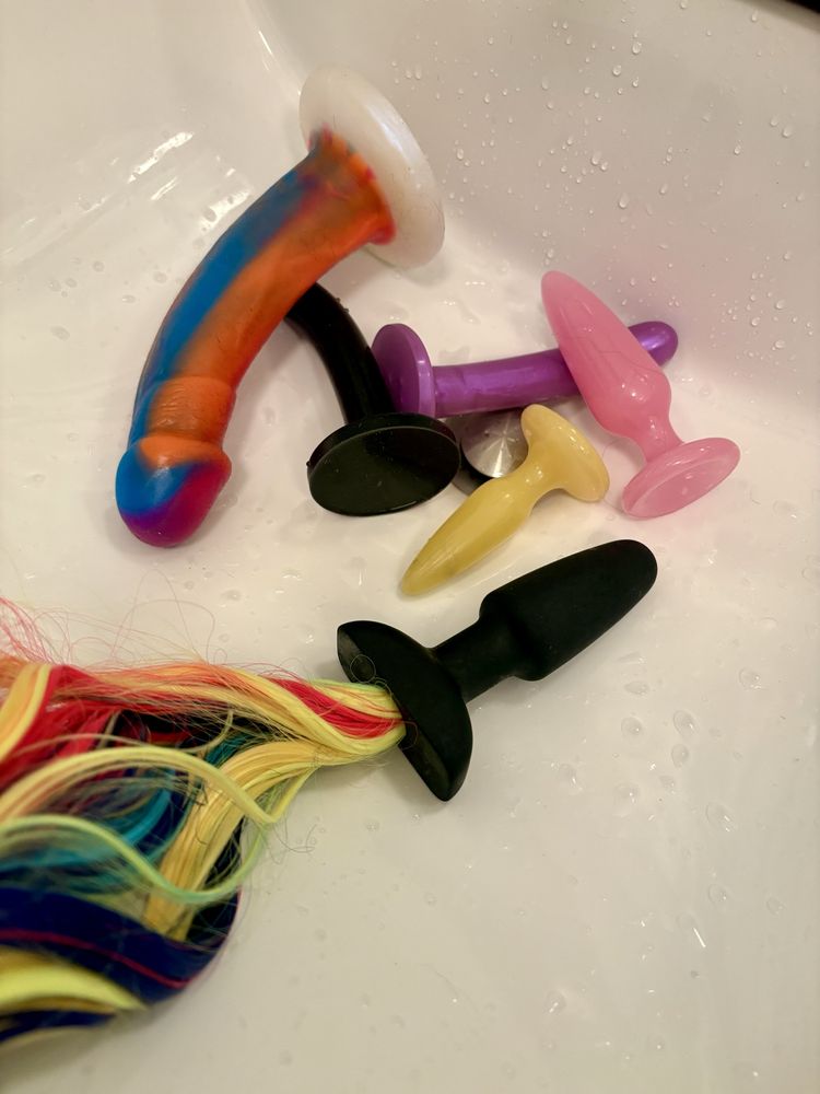 Some of my colorful butt plugs, dildo’s, favorite unicorn tail butt plug, and rainbow cock all clean and now glistening after being used on my queer femme ass. 