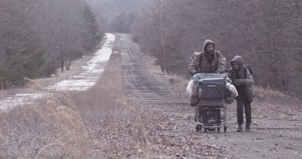 Scene from the movie The Road, where the dad and kid are walking in a desolate, dead landscape of unrelenting brown and grey 