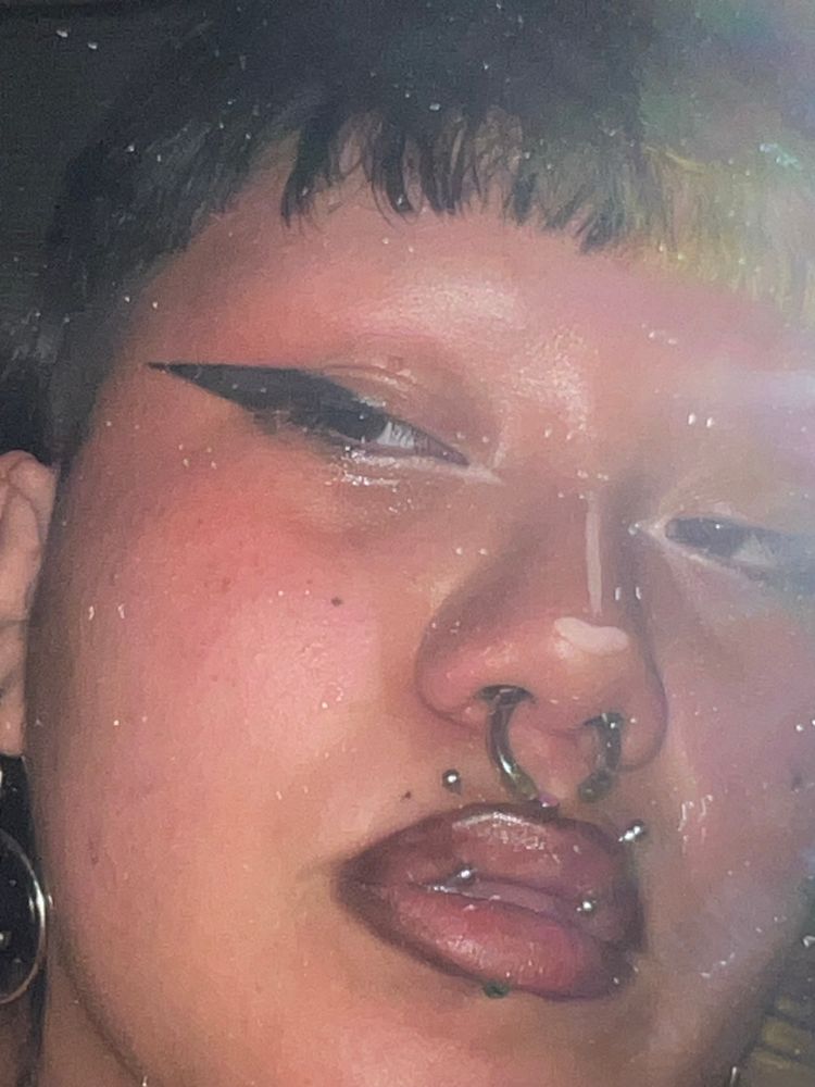 close up of Lux's face in a mirror selfie, eyeliner, nose contour and the have 4 lips piercings and nose piercings 
