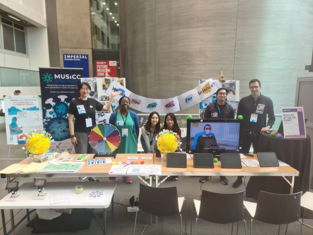 A group of researchers presenting the 'Would you get sick for science stand?' at the Great Exhibition Road Festival 2025. The stand is populated by various banners, posters and activities to engage the public on human challenge studies.