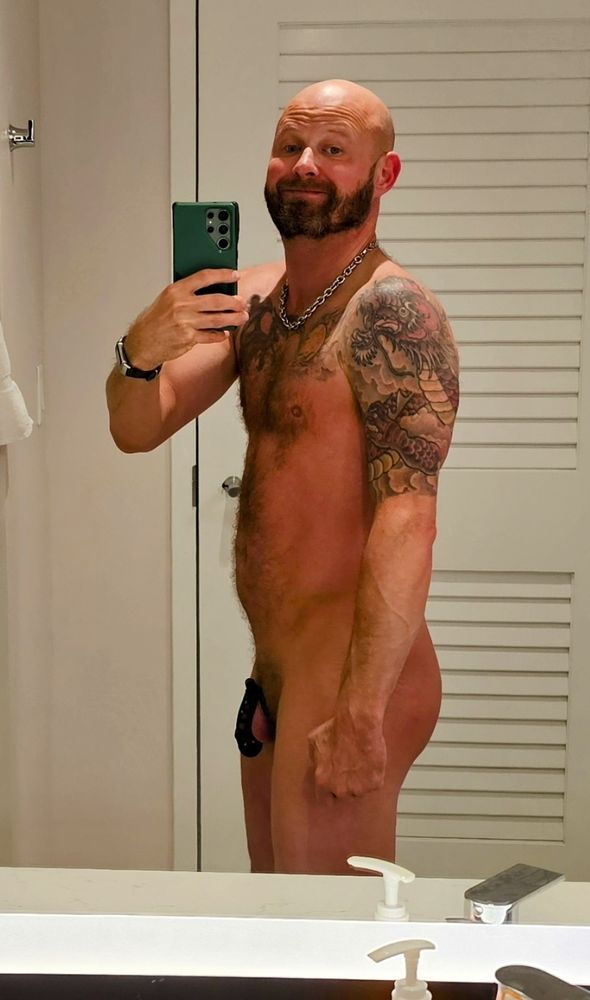 Side view of me in front of a mirror wearing nothing but a cock cage.