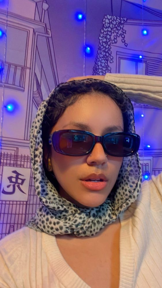 Sopa is wearing a printed scarf around her head reminiscent of an old Hollywood style. Rectangle sunglasses and all.  